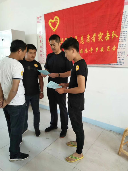 齊剛(右二)正帶領(lǐng)著村青年志愿者突擊隊一起研究改善村容村貌的措施