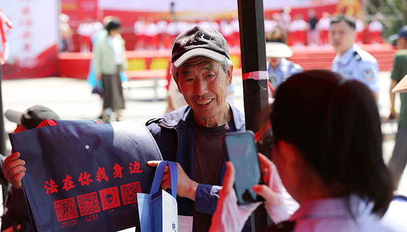 頭題圖，法治文藝節(jié)目展演活動現(xiàn)場，司法局工作人員發(fā)放原創(chuàng)普法購物袋。