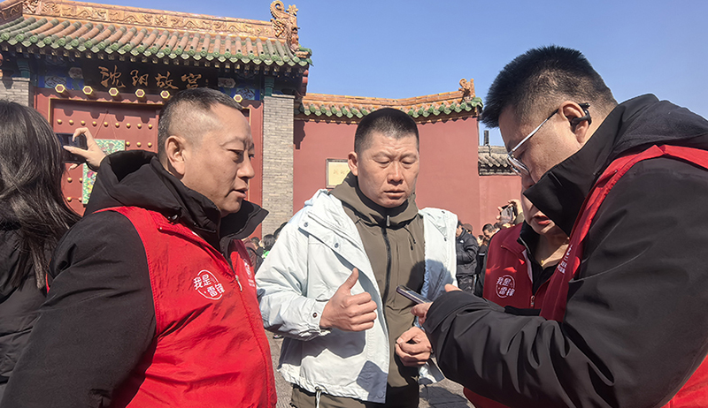 高聰(左)和志愿者正在幫助游客訂票