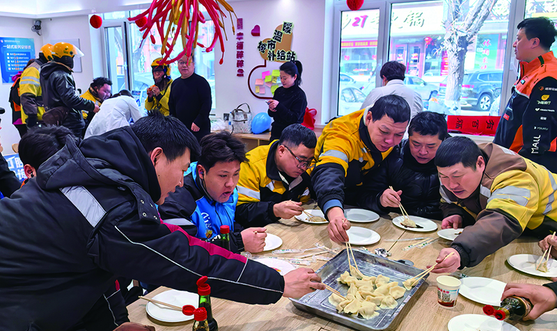 年三十的城市溫暖補(bǔ)給站里，外賣小哥們正吃著熱乎乎的餃子。