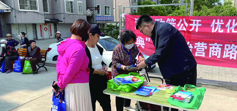 朝陽圖，龍城區(qū)司法局工作人員正在向轄區(qū)居民發(fā)放各類民法典宣傳資料